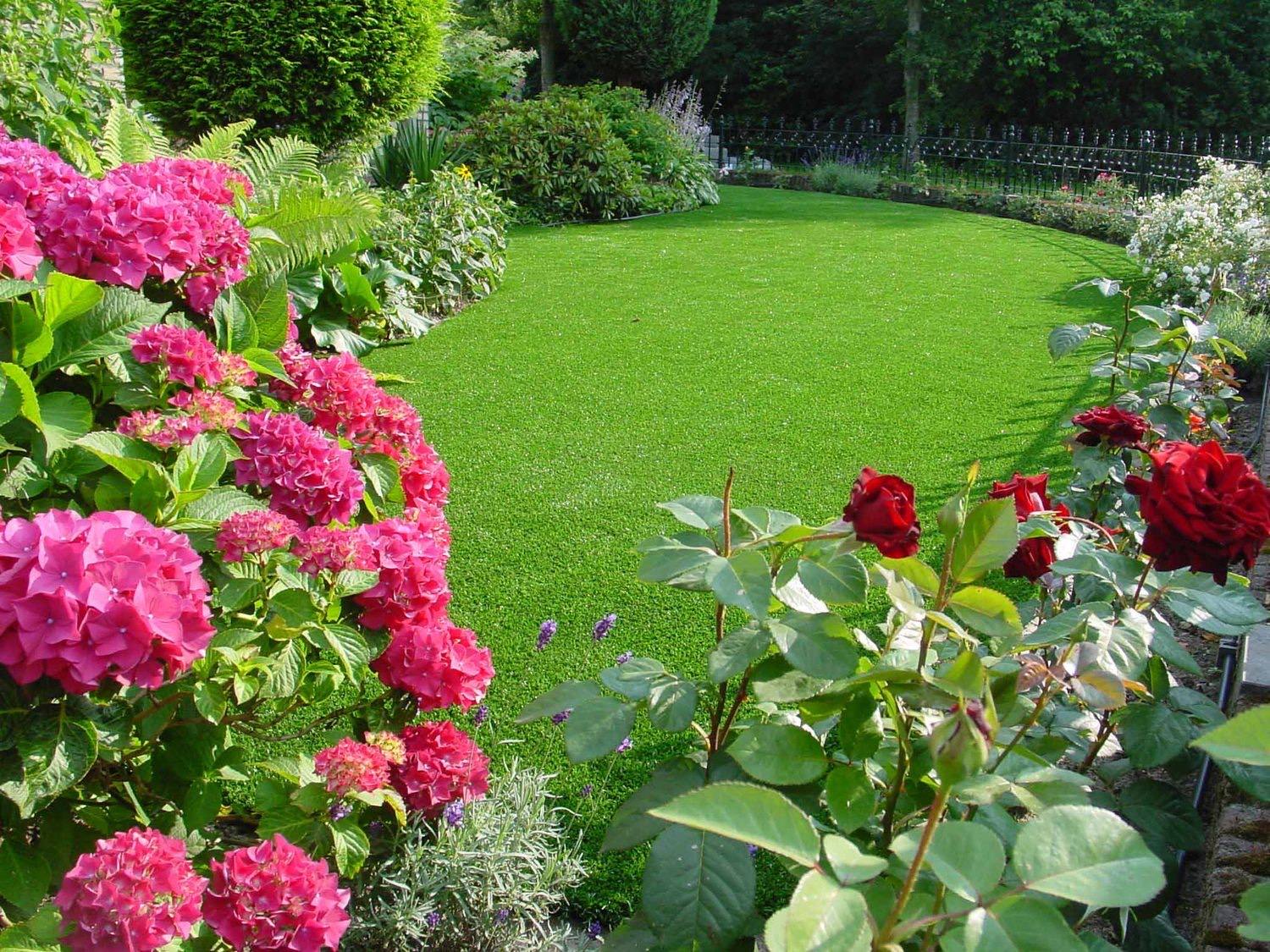 Frodig have med kunstgræs og blomster