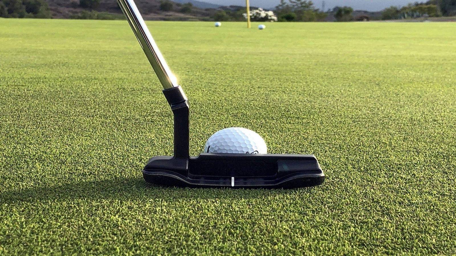 Putter og golfbold på puttinggreen